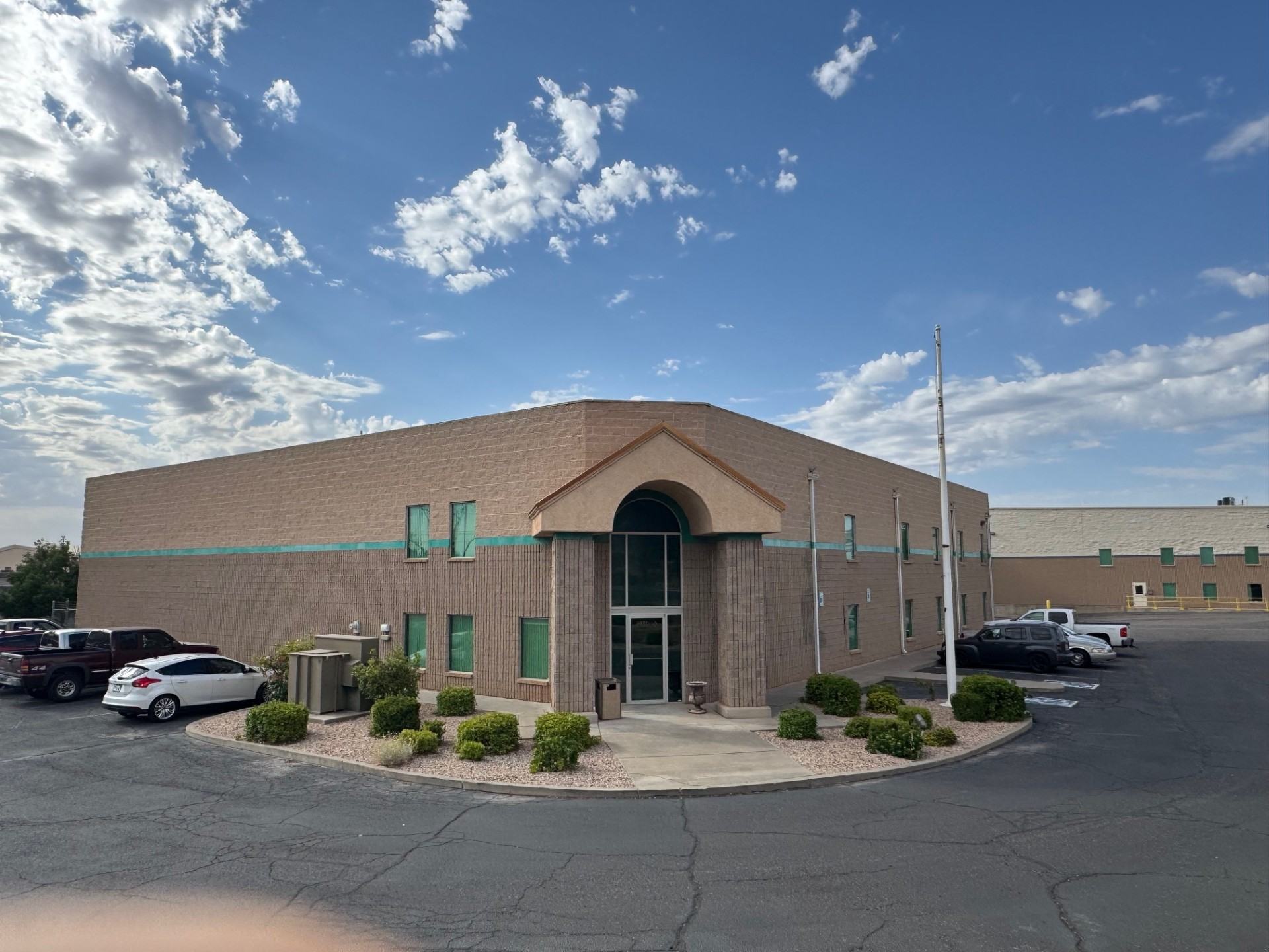 Front entry of the building with arched glass entrance and landscaped walkway