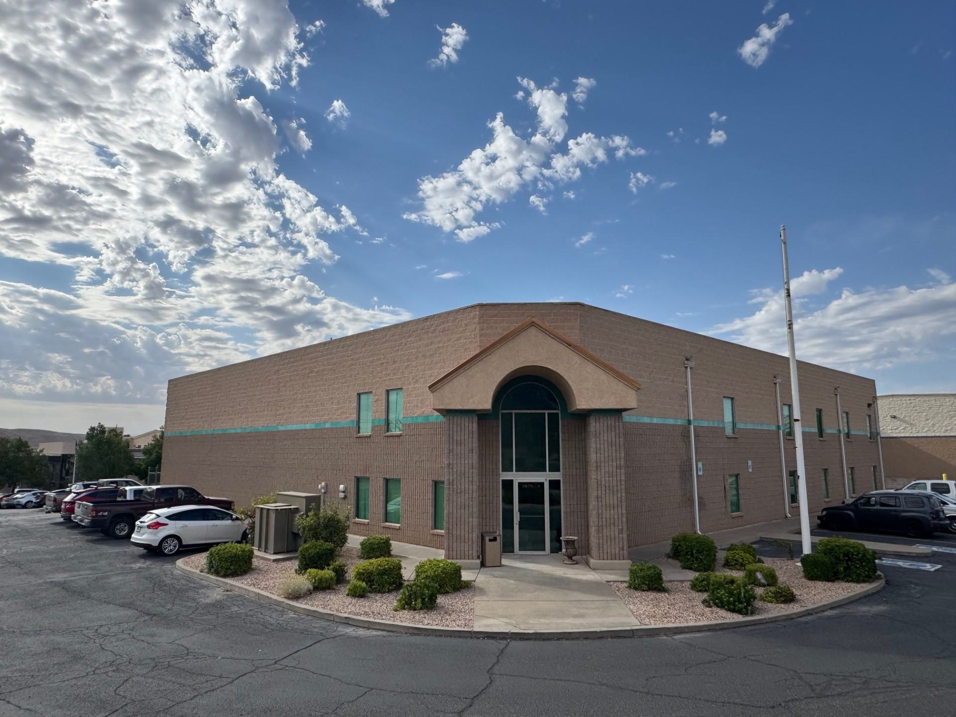 Front corner of 3879 River Road Suite A, a tan masonry warehouse and office building under a blue sky