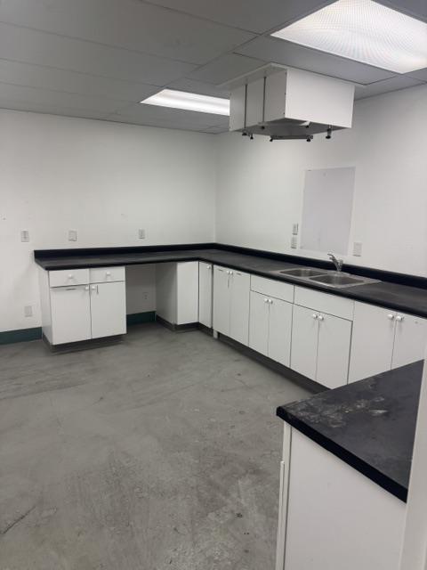 Break room with white cabinets, dark counters and a double sink
