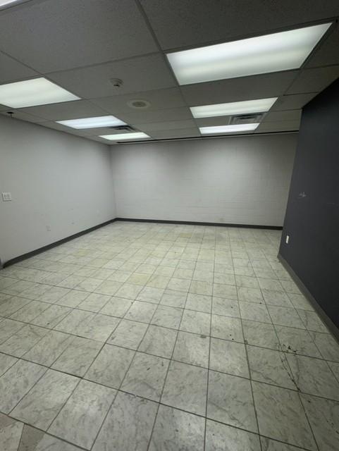 Tiled interior room with drop ceiling and recessed lighting