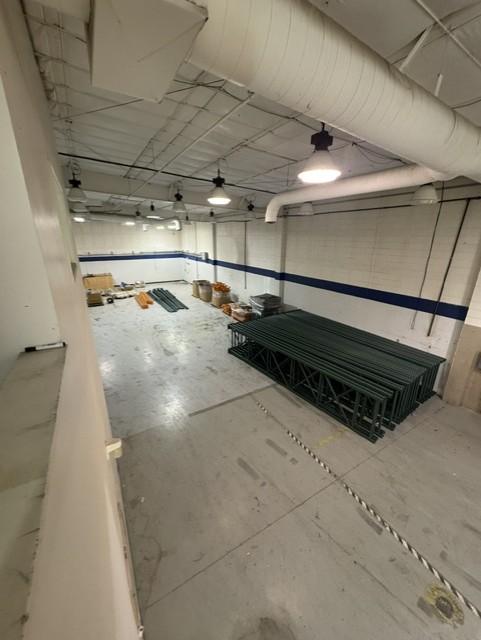 Open warehouse floor with high ceiling, exposed ductwork and high-bay lighting