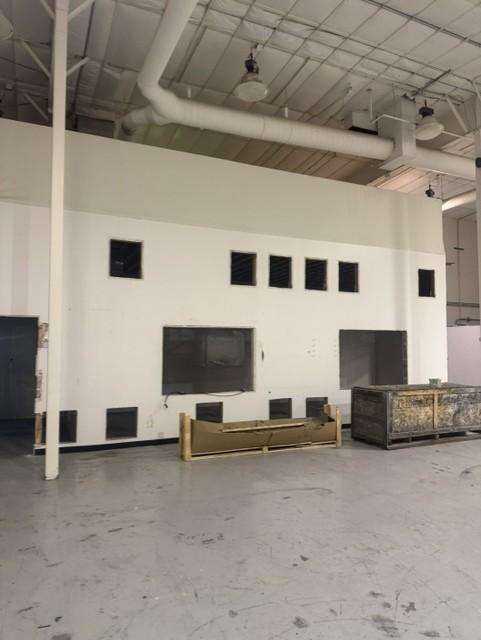 High warehouse wall with ventilation openings and equipment staged on the floor